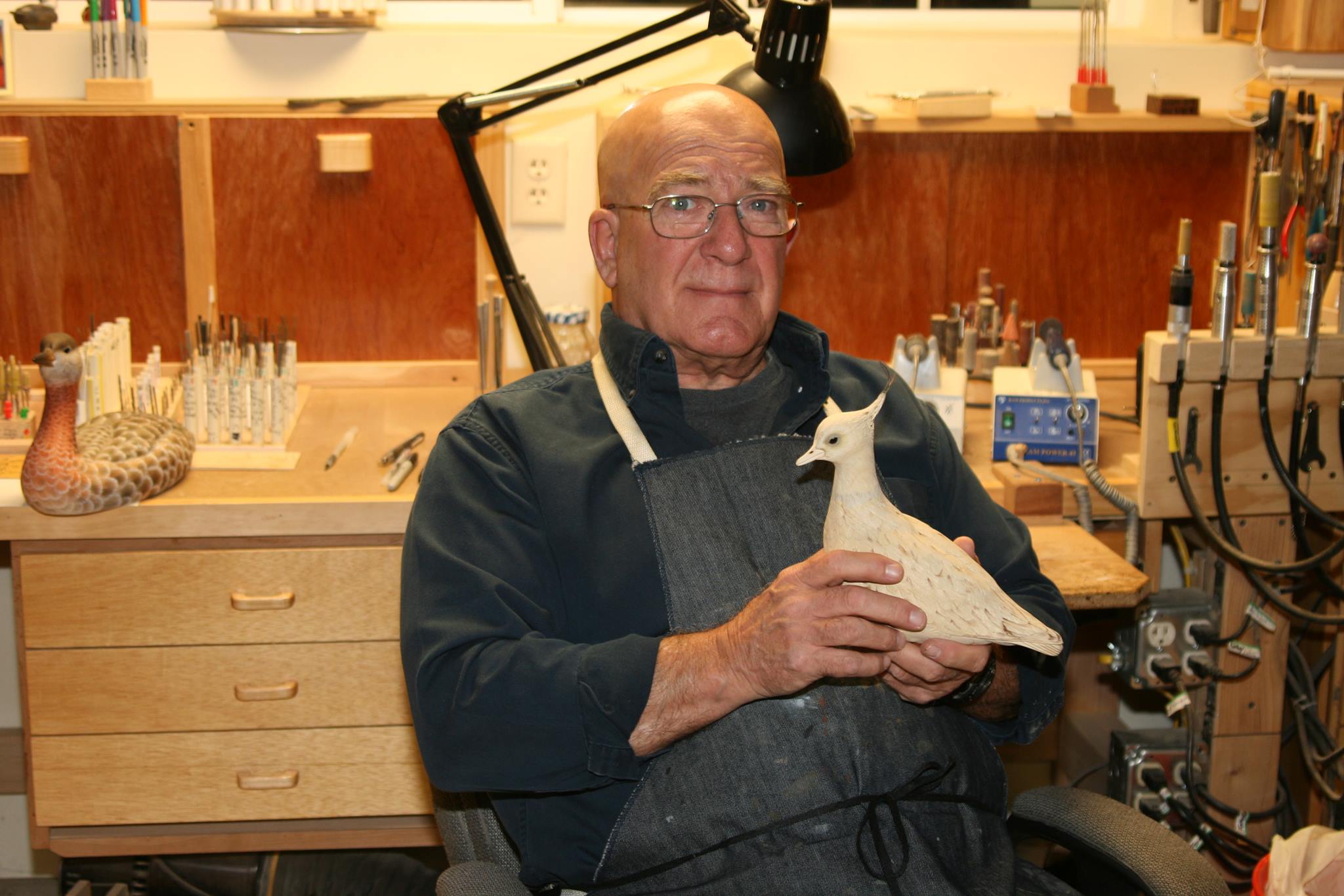 Edward H. Legg in his workshop holding a bird carving